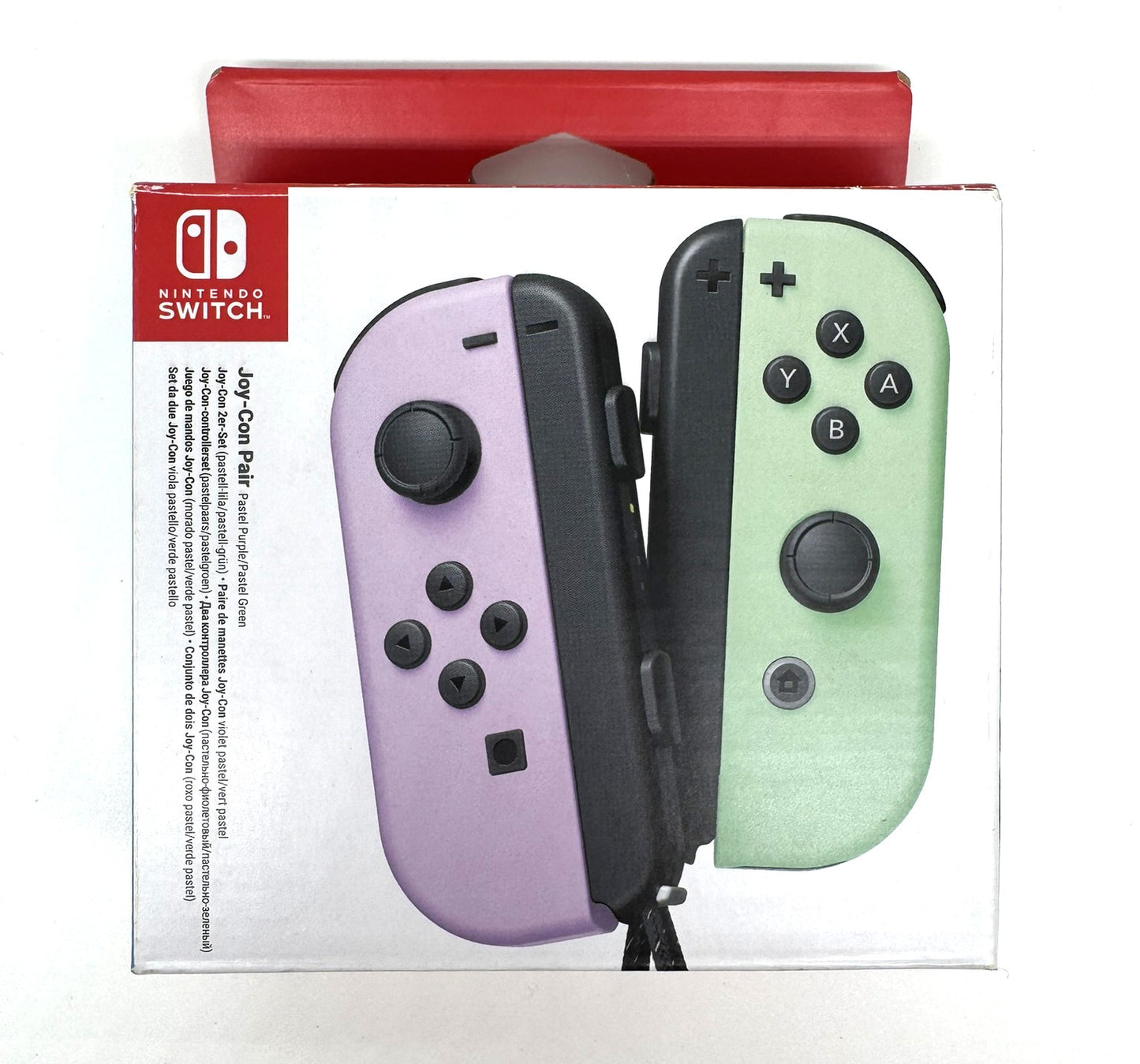 Verpackung eines Joy-Con Paars in Pastellfarben – links lila, rechts mintgrün. Die Nintendo Switch Verpackung zeigt das Design in Großaufnahme auf weißem Hintergrund mit rotem Kopfteil.