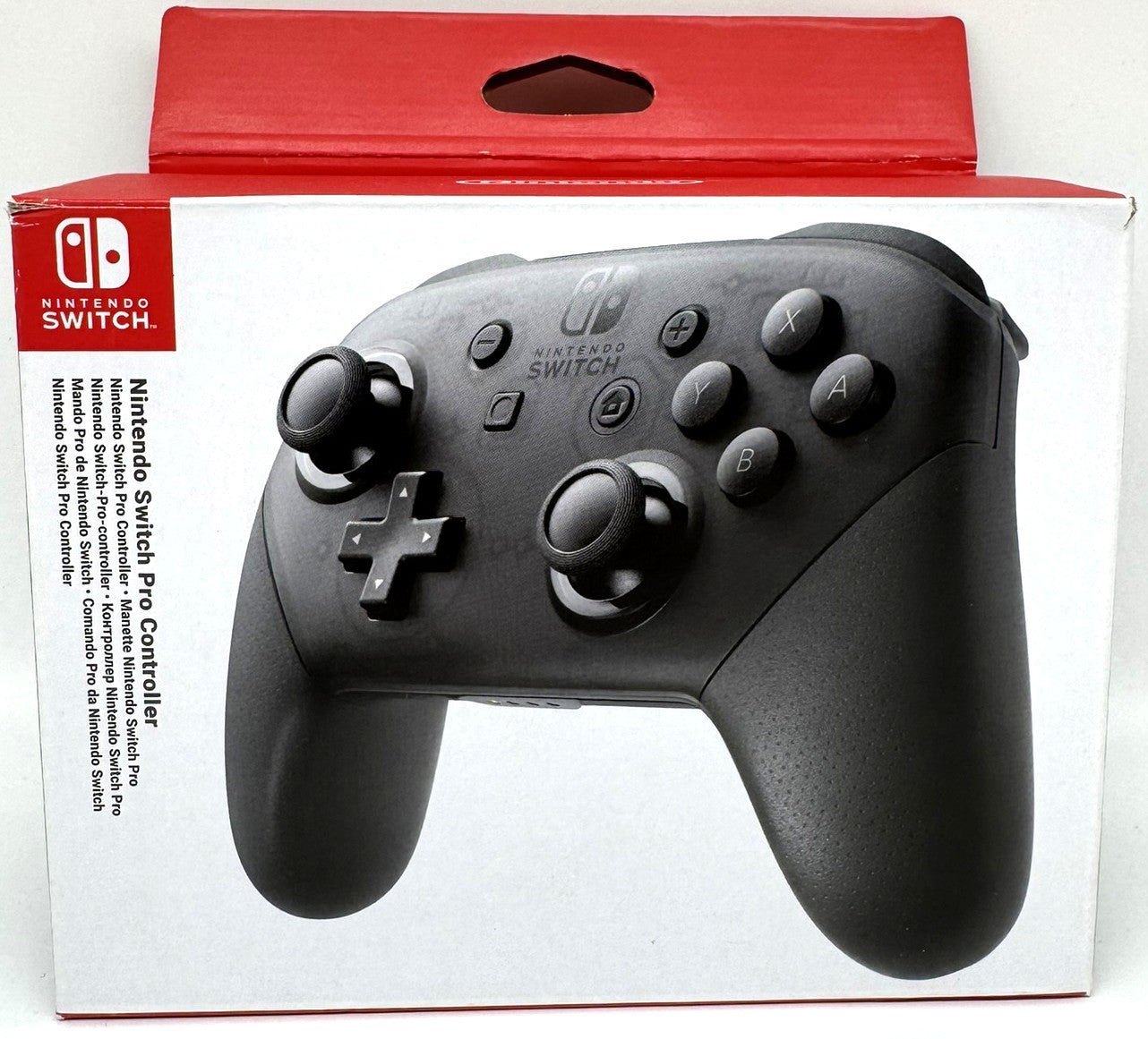 Eine Originalverpackung des Nintendo Switch Pro Controllers in Schwarz Transparent. Vorderseite mit großem Produktbild des Controllers, linksseitig roter Markenrahmen mit „Nintendo Switch Pro Controller“-Schriftzug. Verpackung zeigt alle typischen Bedienelemente des Controllers inkl. D-Pad, Analogsticks, Action-Buttons und Home-Button. Die Box liegt auf hellem Hintergrund und hebt sich gut ab.